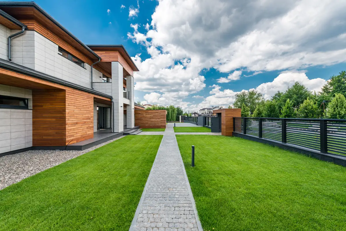 Fachada de casa moderna com jardim e caminho de pedra sob céu azul